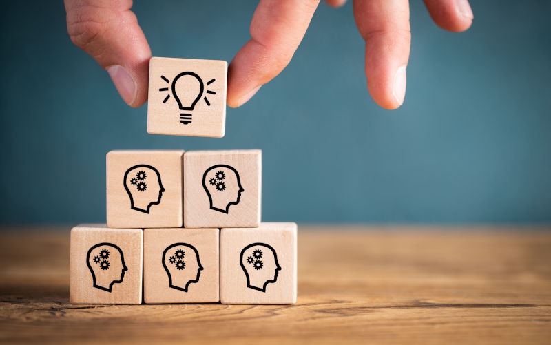 Many people together having an idea symbolised by icons on cubes on wooden background