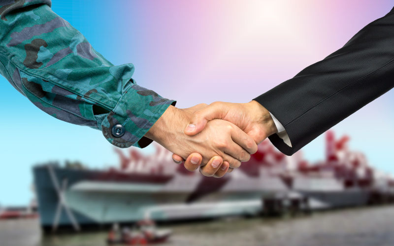 Soldier in uniform and civil man in suit shaking hands.