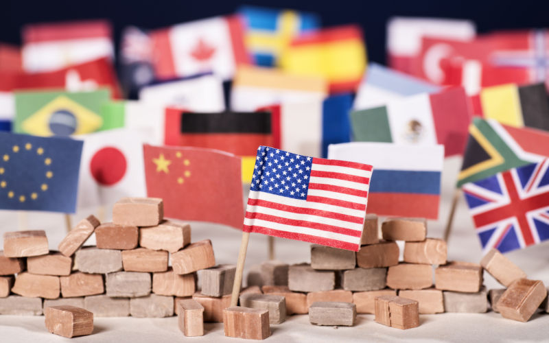 American flag in front of a wall and flags of other countries.