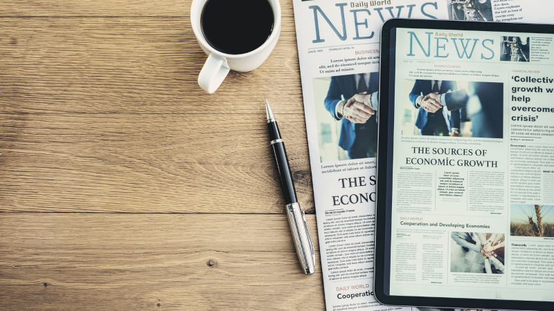 Newspaper and digital tablet on wooden table