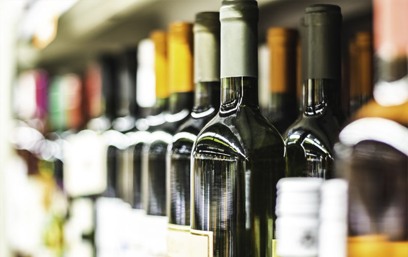 Close up of wine bottles on shelf in store.