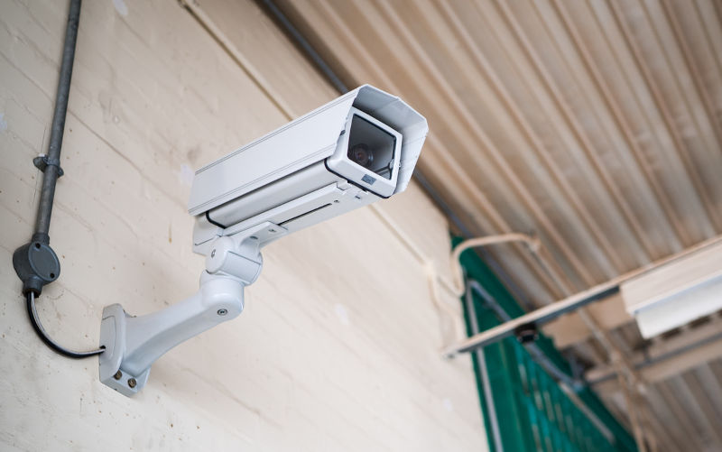 Prison communal room jail in sunlight of high security run down immigration detention centre in England with professional CCTV security camera monitoring the room activity