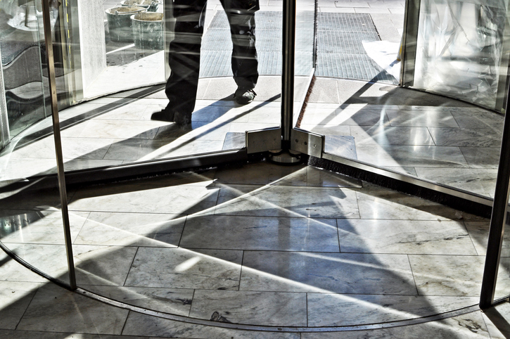 Feet of a businessman walking in revolving door. Image: iStock/AnkiHoglund