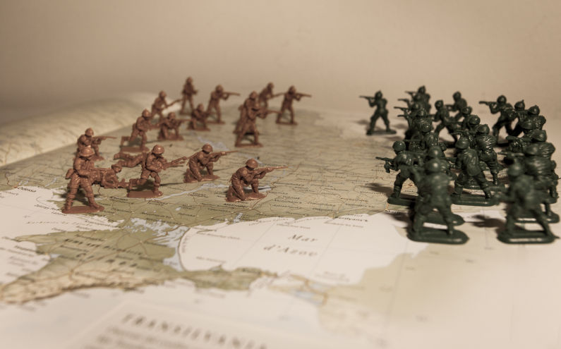 War. Plastic toy soldiers fighting on map.